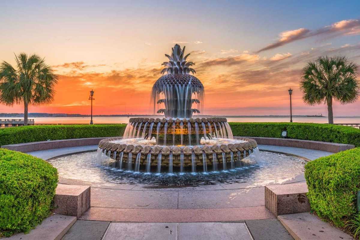 The Pineapple Fountain at Waterfront Park in Charleston SC during a sunset, representing Charleston real estate with Live In Charleston.