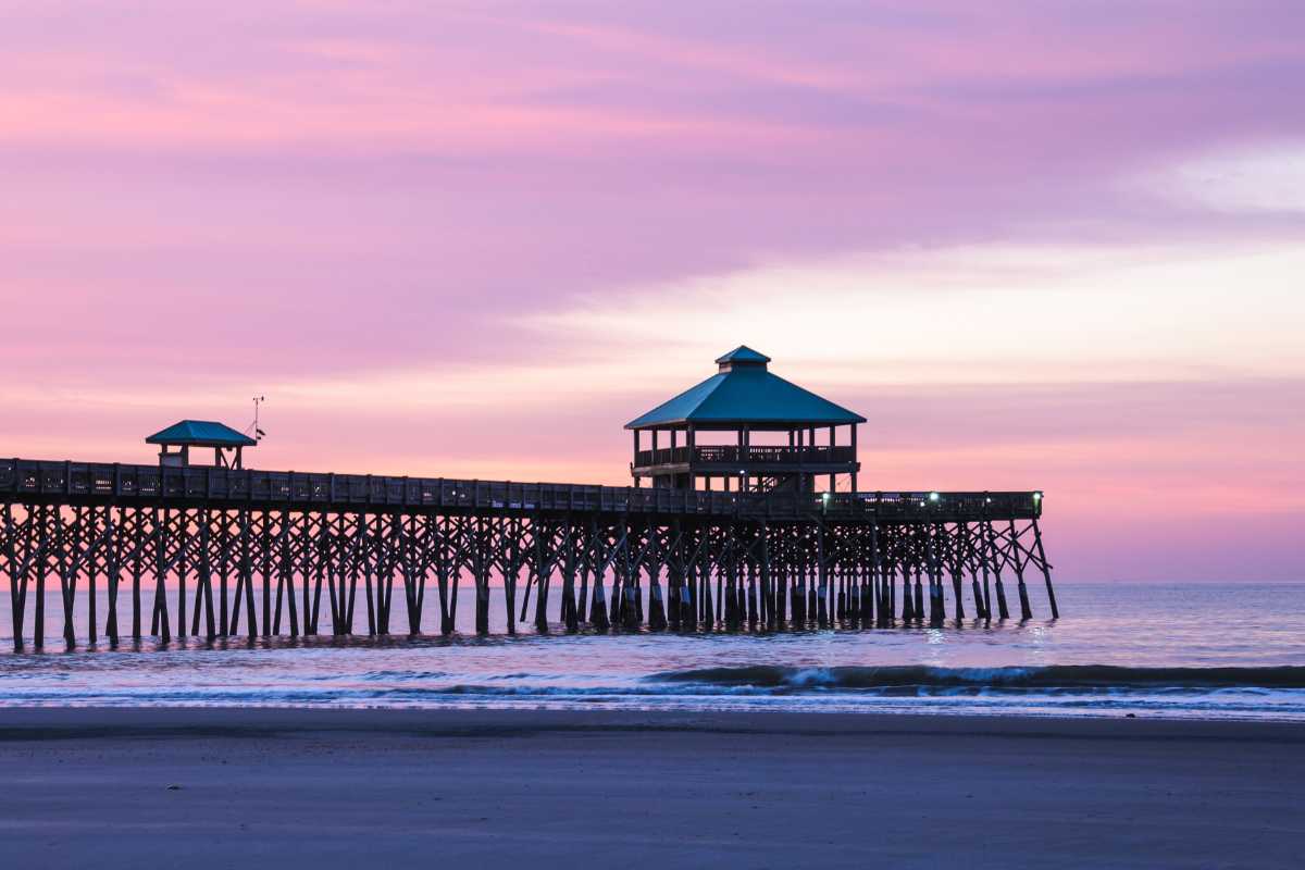 Iconic Folly Beach fishing pier at sunrise, highlighting beachfront living and Folly Beach homes for sale by Live In Charleston.