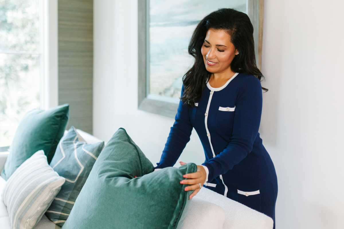 Michelle Almeyda-Wiedemuth adjusting a living room pillow in a Charleston home